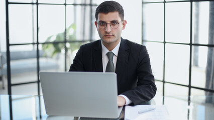 Fototapeta premium handsome business man in an elegant black suit at a laptop