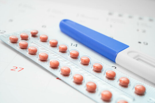 Pregnancy test and birth control pills on calendar, contraception health and medicine.