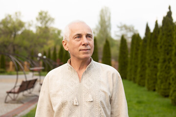 Senior man with gray hair in green nature background