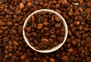 A bowl with coffee beans on the background of coffee beans.