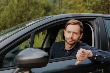 Unhappy driver showing thumbs down in car.