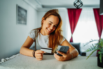 Young caucasian woman shopping online on mobile phone using credit card