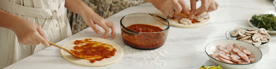 Header with family cooking pizza together in the kitchen