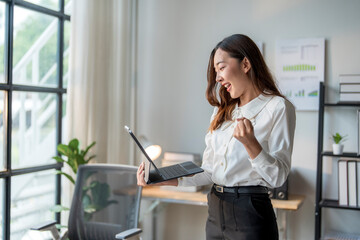 Businesswoman celebrating success looking at tablet in office