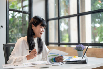 Businesswoman analyzing financial chart using laptop computer in office