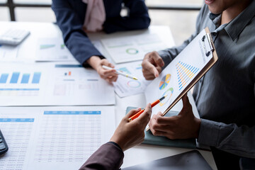 Business team analyzing financial data using charts and graphs on clipboard