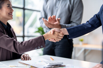 Businesswomen shaking hands while manager is clapping in the background