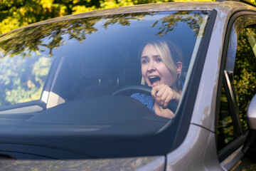 Stressed woman drive car feeling sad and shocked. Caucasian blond girl shouting and feeling...