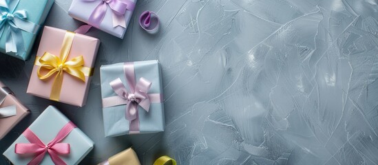 Gift boxes in various pastel hues such as pink, yellow, blue, and violet with ribbon bows displayed on a gray background in a festive arrangement for a copy space image.