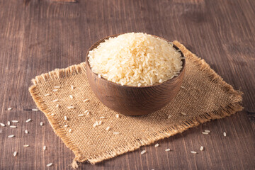 Uncooked white rice in a wooden bowl. Healthy cereal concept.  