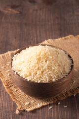 Uncooked white rice in a wooden bowl. Healthy cereal concept.  