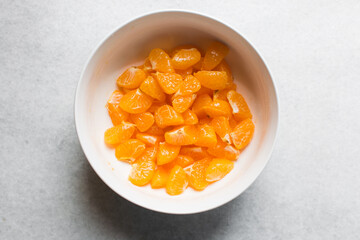 Overhead view of peeled and sliced tangerines in a white ceramic bowl, top view of tangerine pieces in a white mixing bowl