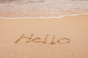 the inscription hello  on the seashore with palm trees