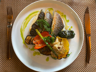 fried fish on a white plate restaurant table setting. Grilled vegetables. Peppers, eggplant, zucchini and asparagus. Beautiful presentation of food. Healthy food, for vegans.