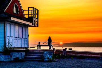 open to possiblity: silhouette of a person watching the sun rise over lake ontario and kew beach...