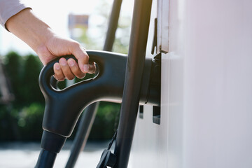 Hand is holding fast electric car charger green energy environment friendly driving vehicle station. Modern transport fuel of future. Minimal design power unit