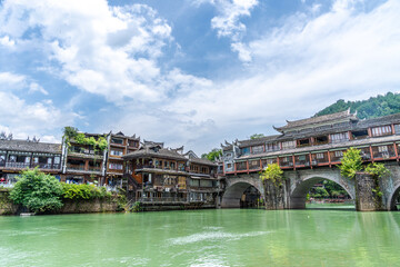 Naklejka premium Green Water and Traditional Miao Village Architecture by the River in Fenghuang Ancient Town, Xiangxi, Hunan