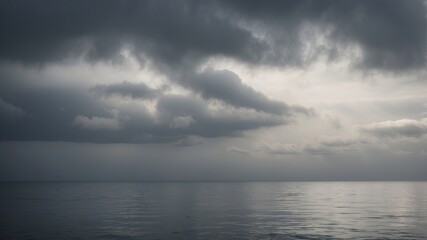 Fototapeta premium A vast, grey sky with clouds rolling over a calm, tranquil sea The horizon is lost in the mist.