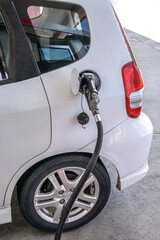 Gasoline Nozzle In Fuel Filler of Small White Car Revised