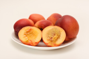 Ripe peaches on a white plate. Juicy fruits.