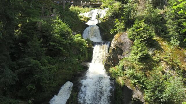 The highest waterfall of the Black Forest in Triberg, Germany. Slow motion of falling clear mountain water in detail. Big rocky stones covered with green moss in a mountain place