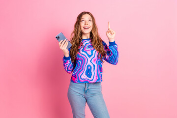 Portrait of nice young girl smart phone direct finger up empty space wear sweater isolated on pink color background