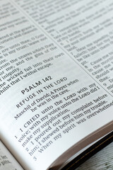 Fototapeta premium Psalm 142, refuge in the LORD biblical verses in open holy bible book. Close-up. Christian concept of God's care, protection, and help in trouble.