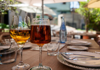 Two wine glasses are on a table with a blue bottle of water