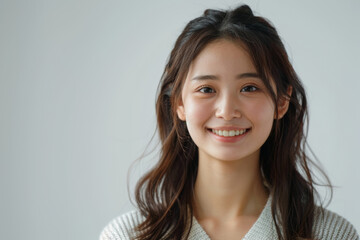 Fototapeta premium A charming Asian woman dressed in elegant white office attire, with a simple and clean design, stands confidently with a professional hairstyle and subtle makeup against a neutral background.
