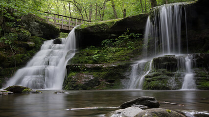 Obraz premium Peaceful Waterfall in a forest under a bridge