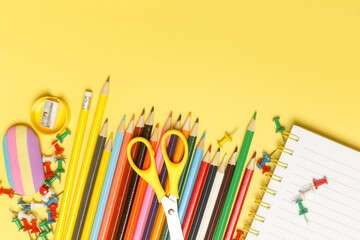 Back to school concept with variety of office and school supplies on yellow background.	