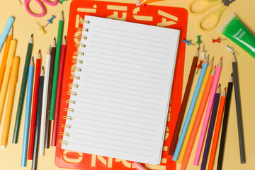 Back to school concept with variety of office and school supplies on yellow background.	