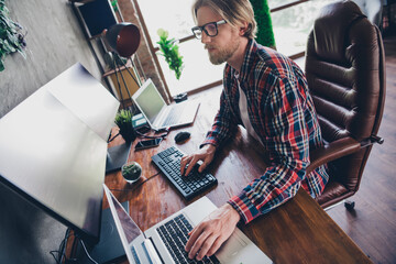 Photo of professional young blond hair hacker guy at loft design modern office using computer coding enjoying keyboard and pc display