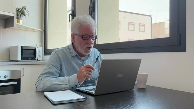 Angry senior businessman arguing animatedly connected in video conference via laptop pc. Handsome bearded mature man arguing annoyed with his interlocutor