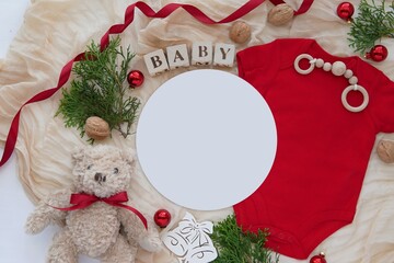 Christmas pregnancy announcement, baby waiting, composition with red baby bodysuit, teddy bear and round card for text or design.