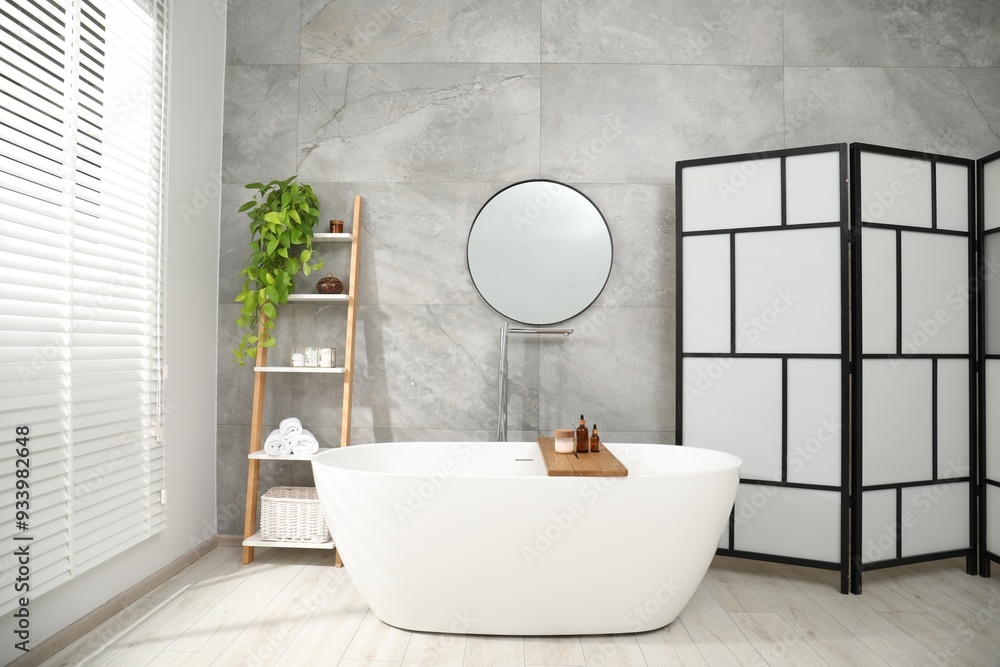 Wall mural Folding screen, bathtub, houseplant and mirror in bathroom. Interior design