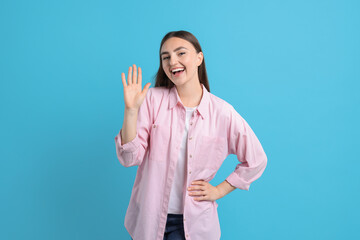 Happy woman waving on light blue background