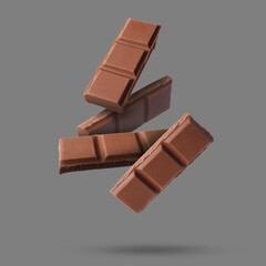 Pieces of sweet chocolate falling on grey background