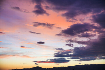 The sky is filled with clouds and the sun is setting, creating a beautiful