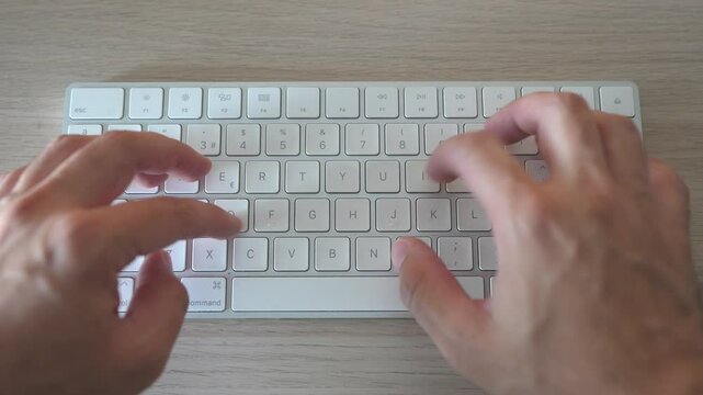 Tecleando en teclado blanco sobre mesa de madera
