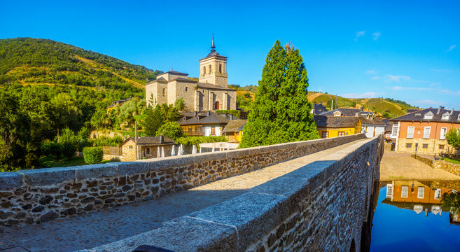 Molinaseca, Spain - August 6, 2024. Molinaseca Pilgrims Bridge, with the Church of San Nicolas de Bari in the background.