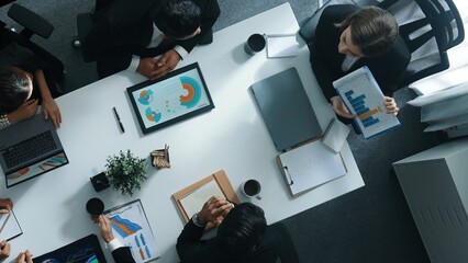 Top view of smart executive manager holding stock market investment chart while planning marketing strategy with diverse group. Smart business team brainstorming and working together. Directorate.