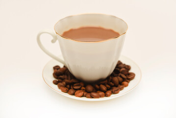 A white cup of coffee and scattered coffee beans.