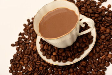 Fototapeta premium A white cup of coffee and scattered coffee beans.