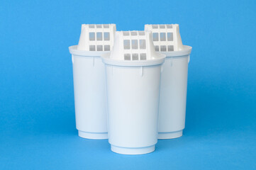 Three water purification cartridges neatly arranged next to each other, on blue background. Water...