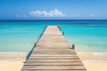 A tranquil wooden pier stretches out over crystal-clear turquoise water under a clear blue sky.