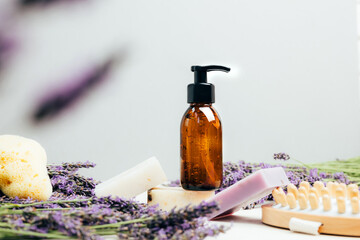 Set of natural cosmetics. Amber bottles with facial, bath liquid on a concrete background with lavender flowers. Front view