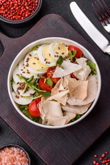 Delicious fresh caesar salad in a bowl with chicken breast, egg, tomatoes