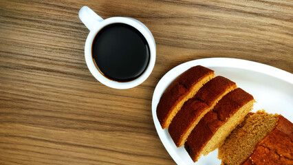 Top view of cinnamon cake, some slices and cup of coffee on the wooden table
