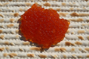 Red caviar on a matzah bread, closeup of photo. Shallow depth of field